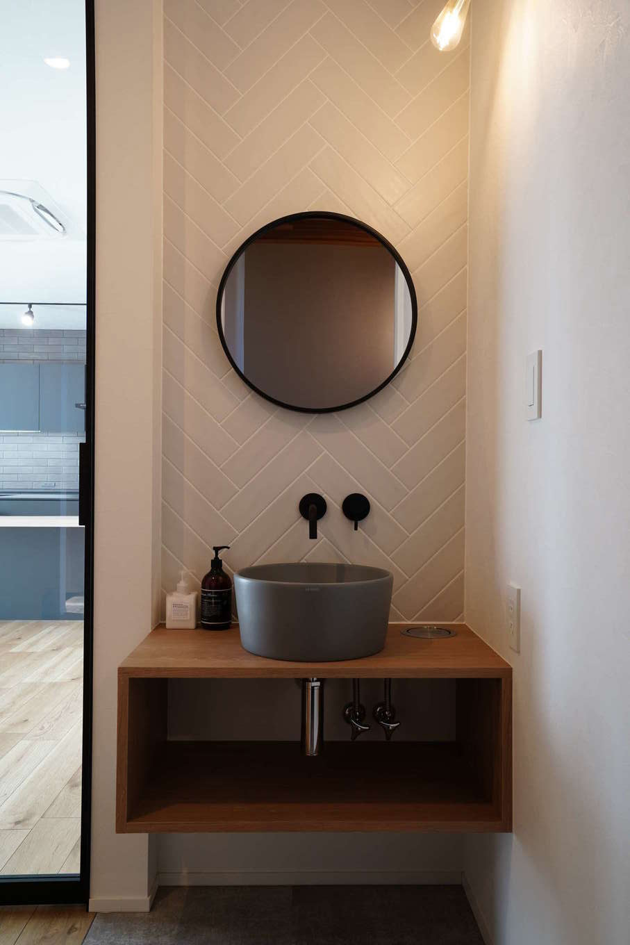 アールスタジオ【デザイン住宅、平屋、インテリア】トイレの側に設けた手洗いスペースは、手洗いボウルと鏡を「丸」で統一。シンプルな四角いカウンターとの組み合わせが絶妙で、空間の意匠性を高めている
