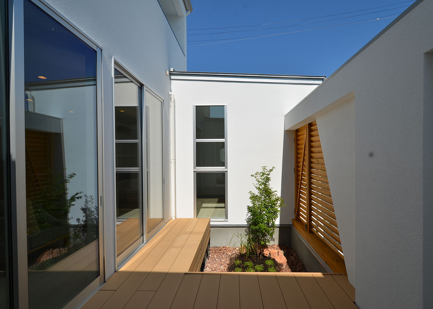 Touch House（タッチハウス）【デザイン住宅、夫婦で暮らす、間取り】中庭には草花が植えられる花壇スペースが設けられた。ウッドデッキの段差をベンチのように腰掛けることもでき、多用途な使い方ができる中庭。暮らしの楽しみが広がる