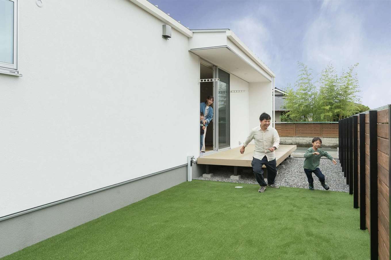 ひだまり工房【デザイン住宅、間取り、平屋】リビングの掃き出し窓からつながる、ウッドデッキと人工芝のプライベートガーデン。ウッドフェンスで緩やかに目隠ししながらBBQや子どもプール、サッカーまでも楽しめる