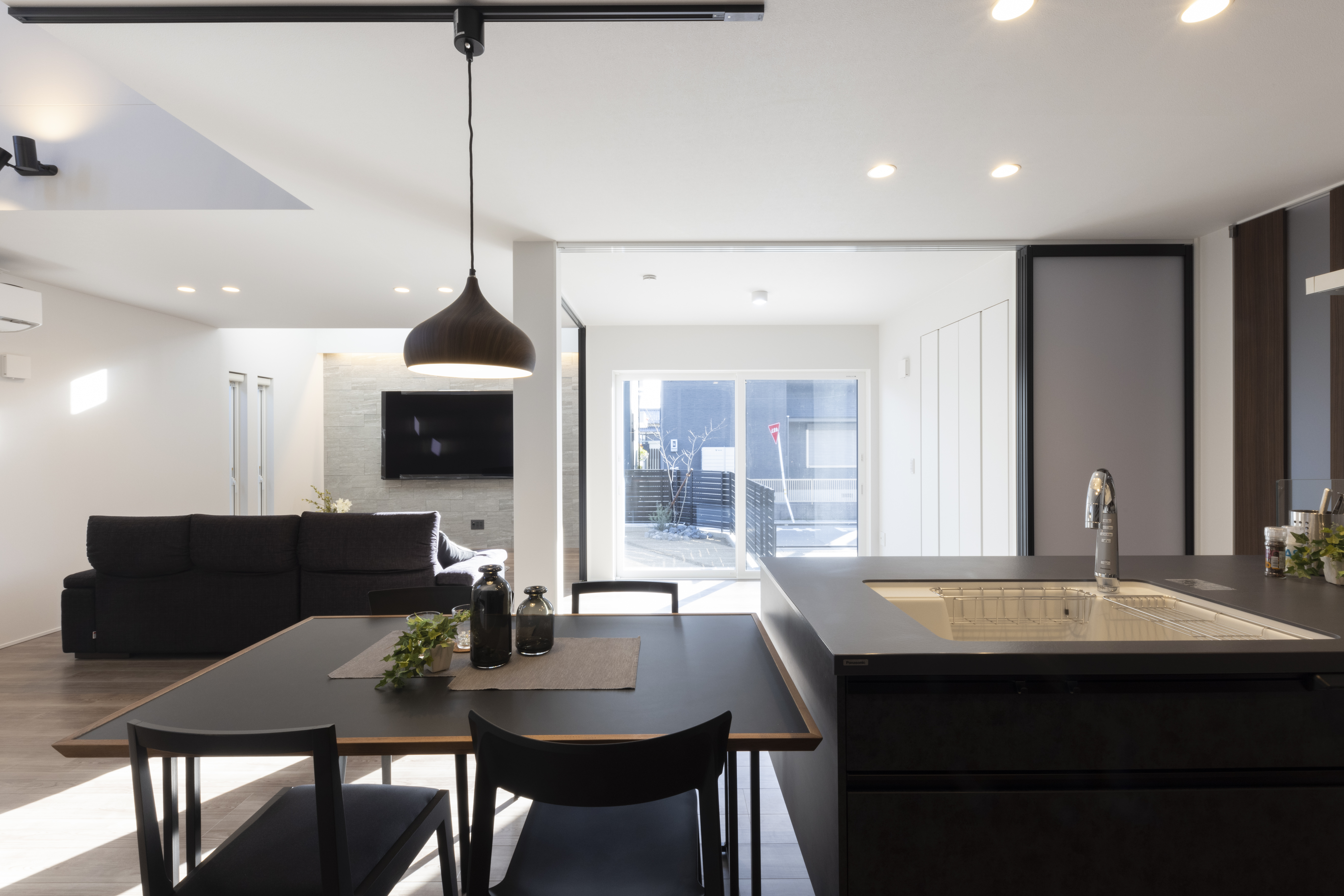 フェスティナ・レンテ｜モダンなデザインのLDK空間で、広々としたリビングにダイニングセットとキッチンがフラットに配置され、家族が自然に集まる雰囲気を演出している。