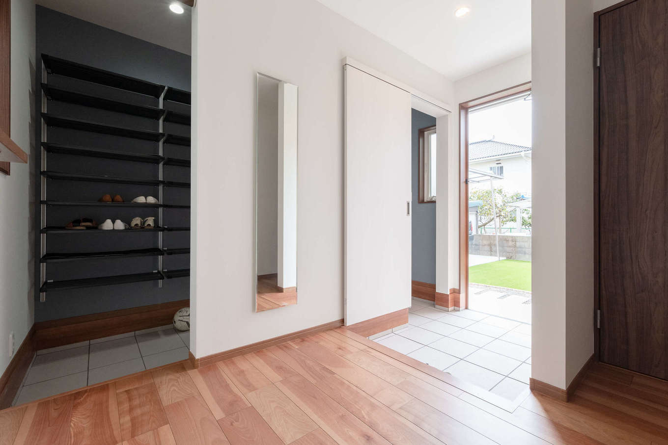 ホームプラザ大東【デザイン住宅、子育て、収納力】帰宅を軽やかな気分にしてくれる明るい玄関。シューズクロークの両側に棚が備えられ、靴や雨具に加え、ベビーカー、三輪車、サッカーグッズなどをたっぷり収納。常に玄関のキレイを保つことができる。姿見や左手の飾り棚も取り付けてもらった