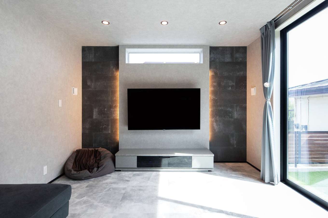 工藤建設【デザイン住宅、子育て、間取り】テレビボードにも間接照明を。スリット窓は天井に近い位置に設置し、視線を上へ促し、視覚的に縦空間の広がりを感じさせる