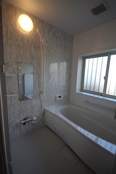 モダンでシンプルなデザインのバスルーム。窓から自然光が差し込み、明るく清潔感のある空間を演出している