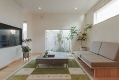 ホームシアター感覚でゆったりとくつろげるリビング。大きなFIX窓に映る中庭のビオトープは、額縁で切り取った写真のように見える。まさに“感情がデザインされる”空間だ