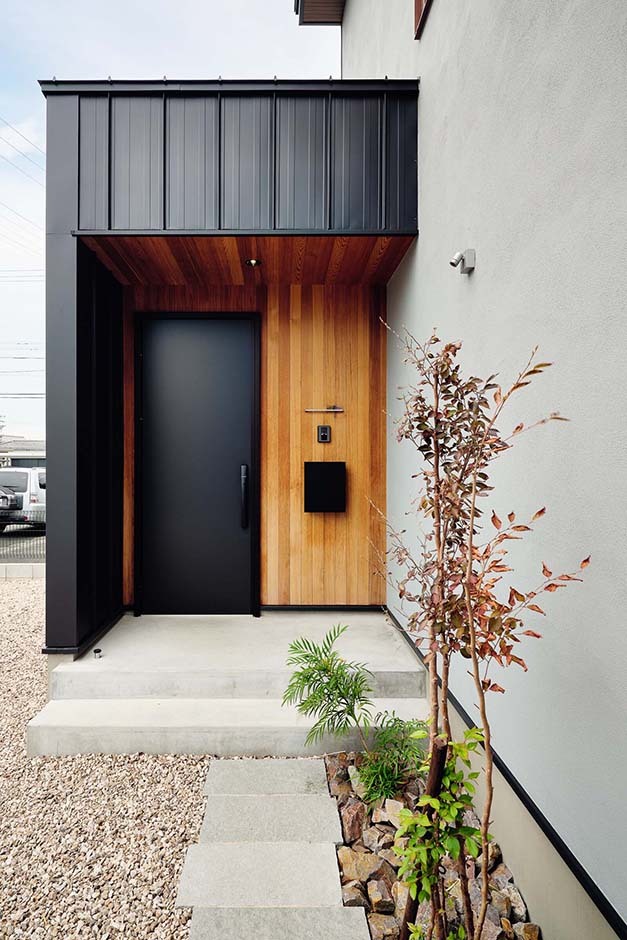 道路側を壁で覆い、周囲からの視線をカットした玄関ポーチ。ウェスタンレッドシダーの無垢板張りの壁は、黒い外壁や玄関ドアと相性抜群