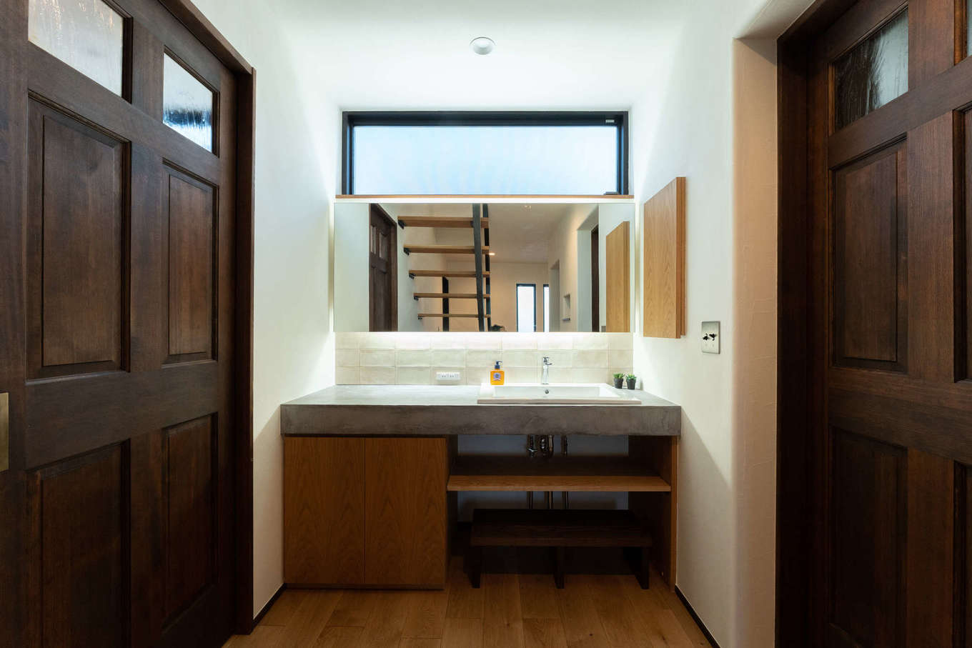 バルハウス【デザイン住宅、自然素材、間取り】モールテックスの天板にナチュラルな扉を組合せた造作の洗面台。鏡の間接照明がホテルライクな印象を与える。ハイサイドライトからの光が、北面とは思えない明るさを届けてくれる