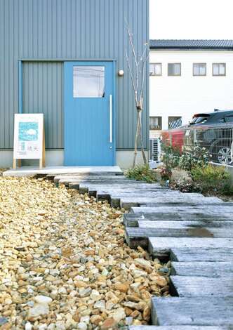 入政建築｜フェアトレード雑貨店「晴天」へのアプローチ。枕木のわきを四季の草花が彩る