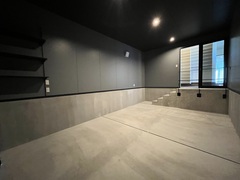 コンクリート仕上げのクールなガレージ空間。シンプルで高級感があり、愛車の手入れや工具の収納に適している設計です。