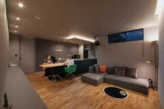 壁と天井はシックなグレー、床は濃い目の無垢。キッチンや家具もトーンをそろえ、ほっとくつげる空間に仕上がった。折り下げ天井とカーテンボックスの間接照明がぬくもりを添える