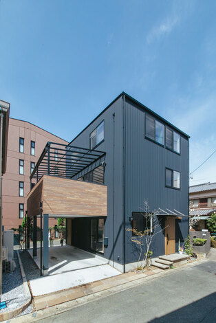 ガルバリウム鋼板と木目をバランスよく組み合わせた外観。車2台が収まる駐車場の真上にテラスを設計し、コンパクトにまとめている