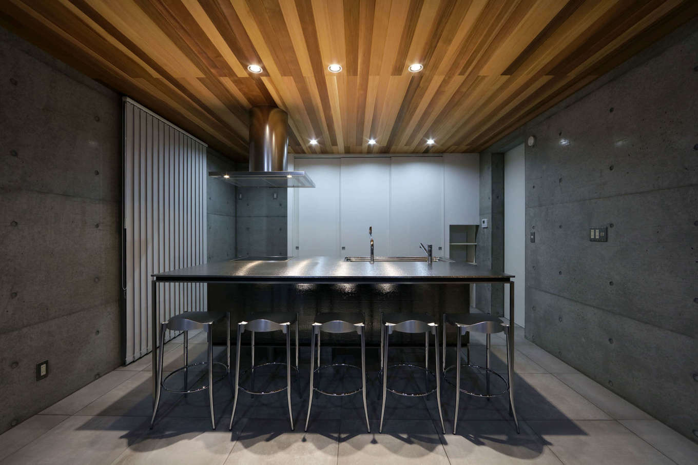 BAUM HOME（岩崎工務店）【デザイン住宅、平屋、鉄骨鉄筋コンクリート構造】リビング側からキッチンを望むと、まるでバーカウンターの様な雰囲気。シルバー＆グレーを基調とした空間に⽊⽬のブラウンがアクセントをつける