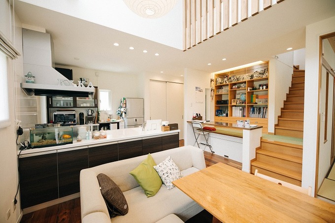開放感あるダイニングキッチン。キッチンからリビング全体を見渡せるレイアウトで、家族とのコミュニケーションを楽しめる空間になっている。階段がアクセントとして配置され、温かみのあるデザインとなっている。