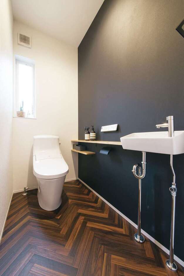 トイレはヘリンボーンの床と黒い壁でシックな雰囲気に。テイストをガラリと変えて、遊びを加えた