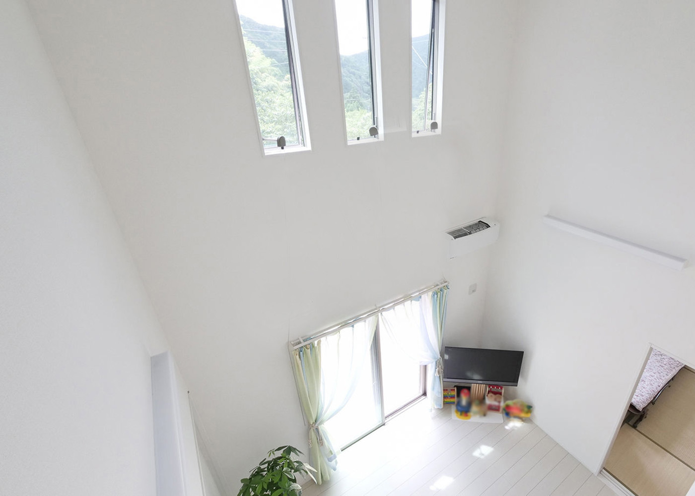 アイダ設計　静岡・愛知【デザイン住宅、子育て、二世帯住宅】リビングはダイナミックな吹き抜けを採用して、いっそうの明るさと開放感をプラス。吹き抜け上部に配した3連の縦長窓や1階の開口部から、自然光がやさしく室内に注がれる
