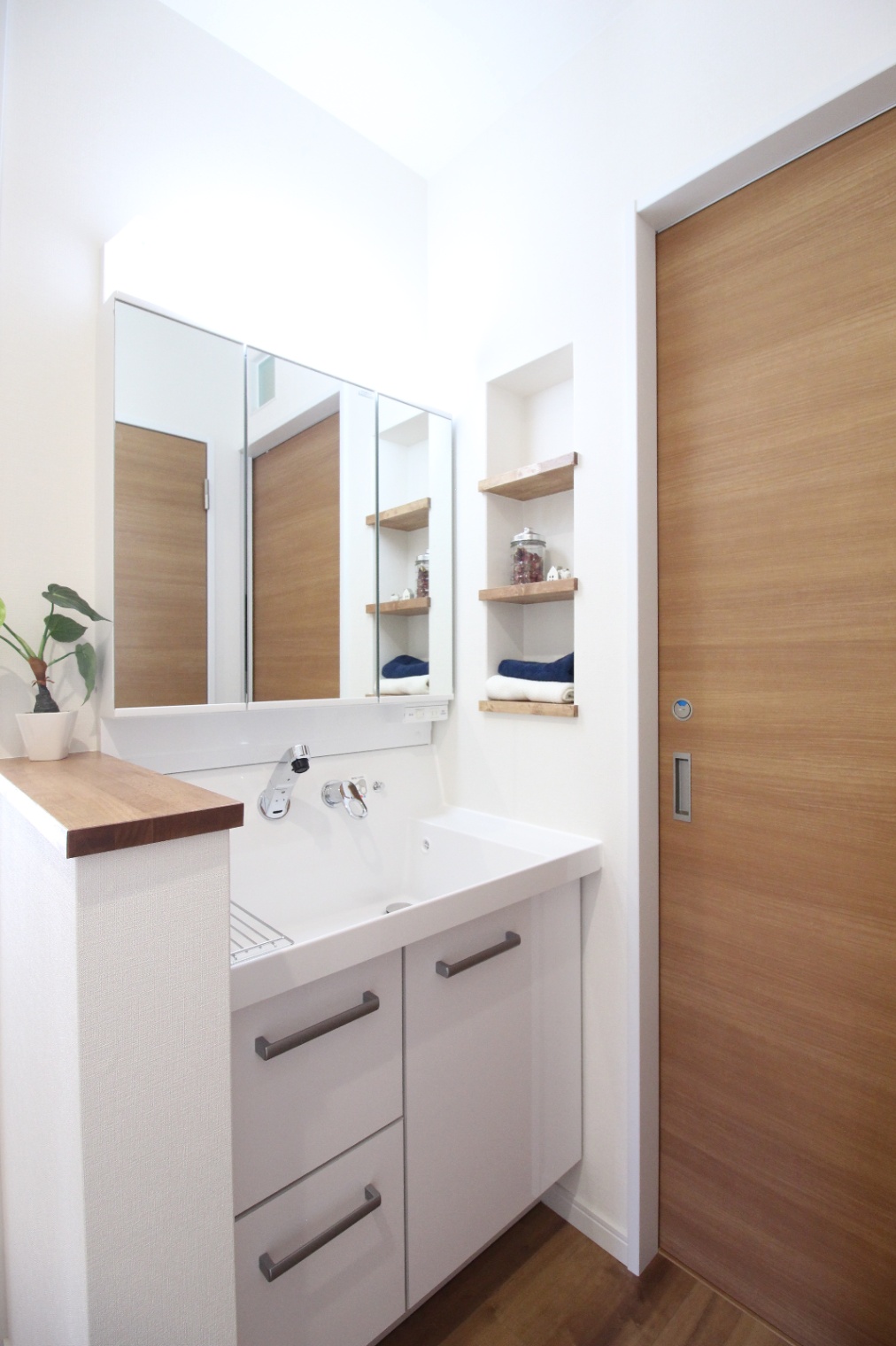 小野田産業～designers house project～｜機能的な洗面スペース。大きな鏡と白を基調としたシンプルなデザインが、清潔感を引き立てる。使いやすい収納も備えられている。