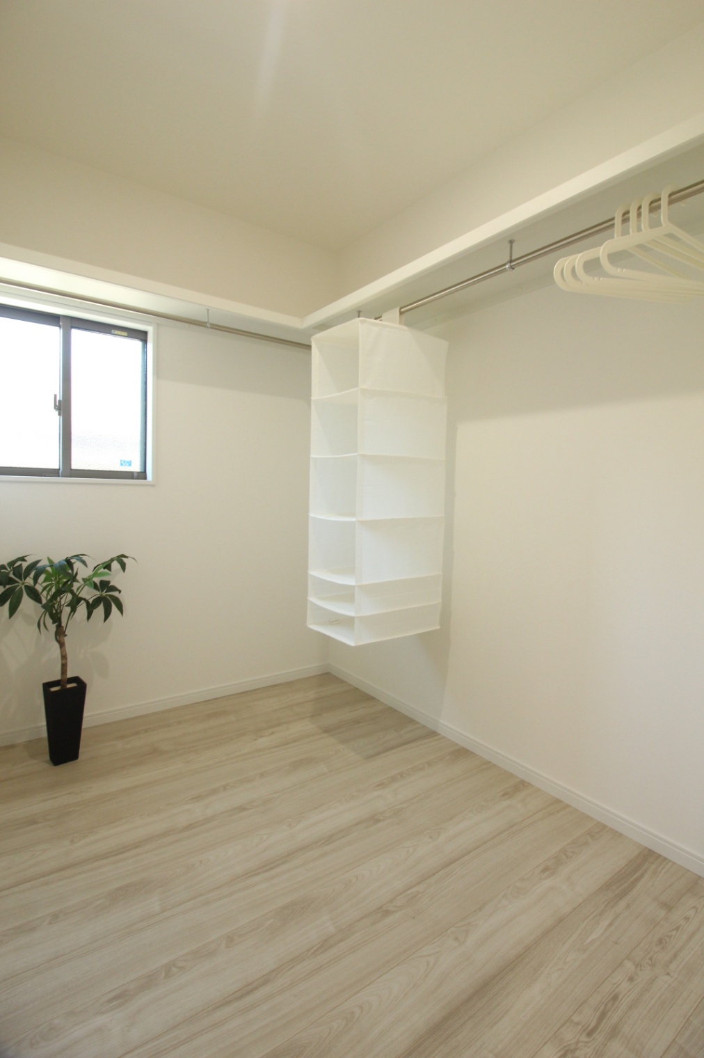 小野田産業～designers house project～｜広々としたウォークインクローゼット。収納棚が充実しており、効率的に衣類を整理できる空間である。明るい窓から自然光が差し込み、開放感もある。