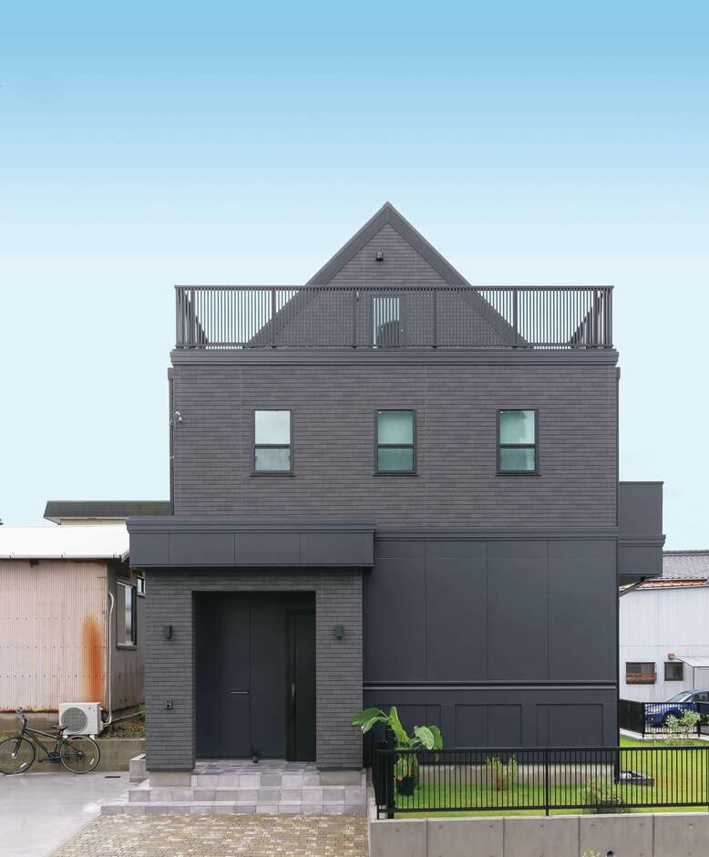 住宅街でひときわ目を惹く独創的な外観フォルム。ブラックの壁に緑の芝生が映える