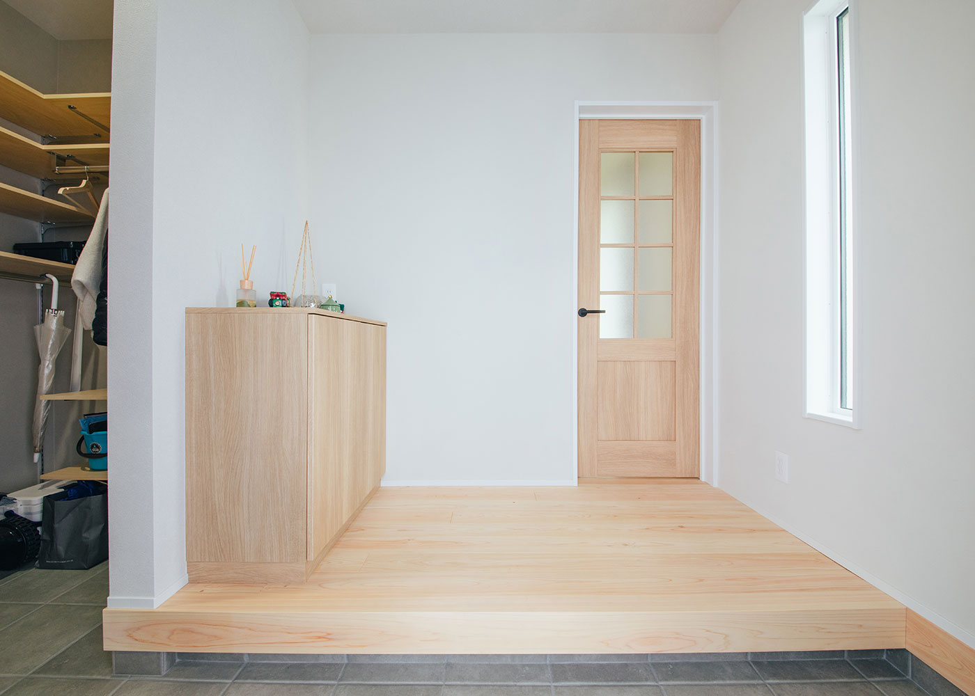 フジモクの家（富士木材）【自然素材、狭小住宅、省エネ】玄関から無垢が敷かれ、壁には珪藻土が採用される。広めに取られた土間収納は、可動棚や姿見を備え、使い勝手がいい