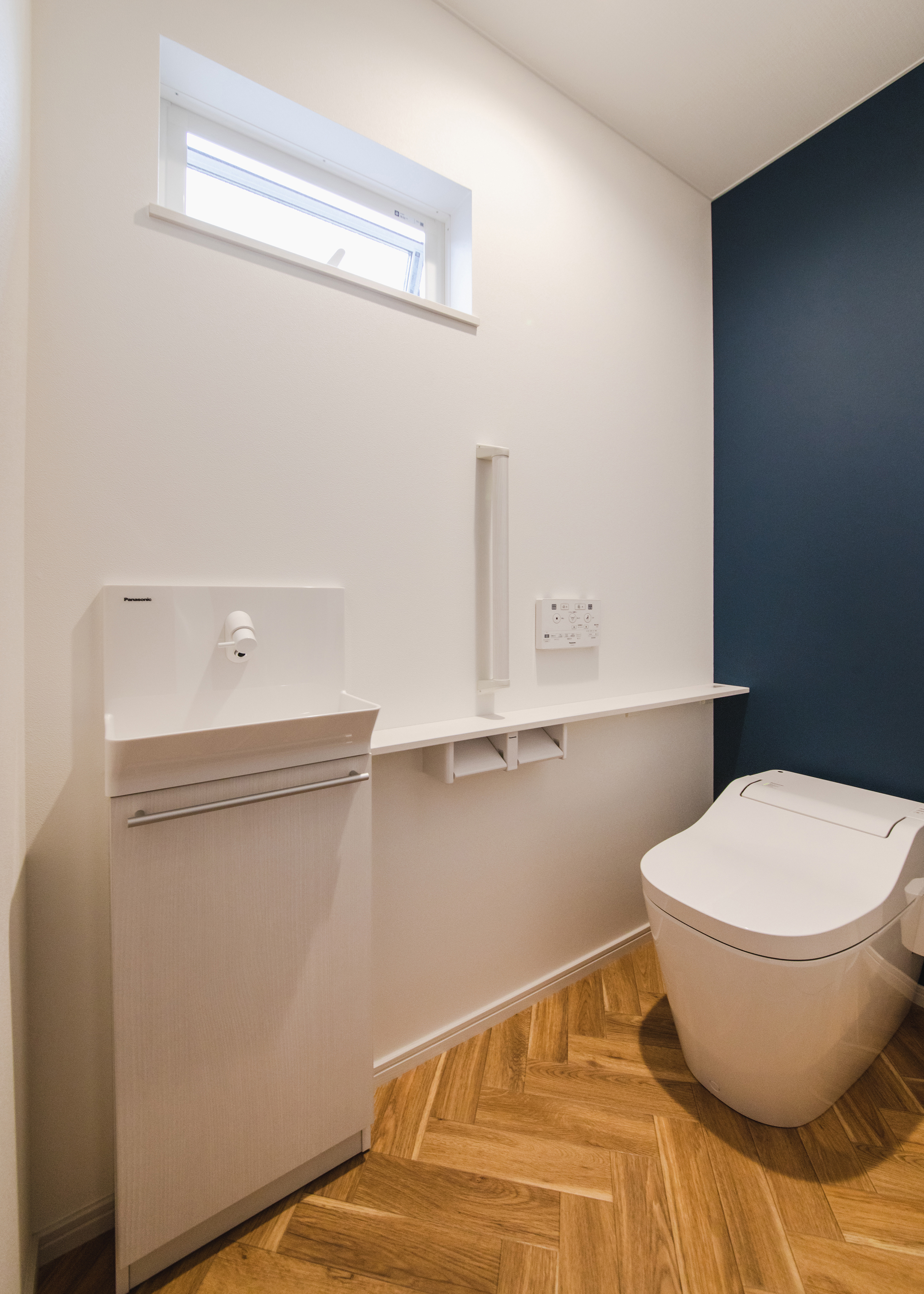 ナイスホーム【収納力、デザイン住宅、間取り】1階のトイレはタンクレスタイプ。ネイビーのクロスとヘリンボーン柄のフロアマットがアクセントに
