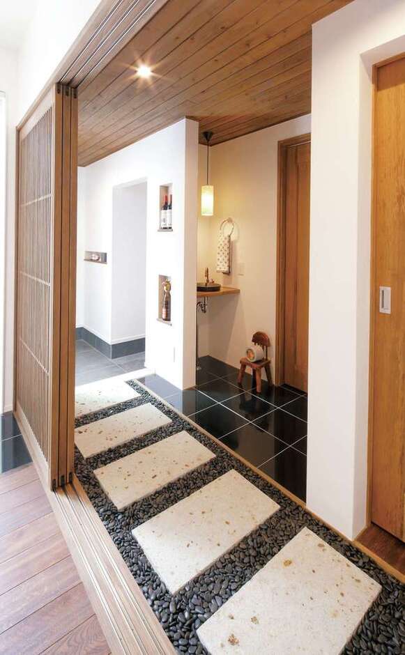 玄関から坪庭に続く廊下は旅館のような趣き。「リビングに着くまでの間も楽しめる遊び心がうれしい」とNさん。ニッチの棚には思い出のつまったワインをディスプレイ