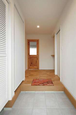 白い空間に無垢の素材感が引き立つ、シューズクローク付きの玄関