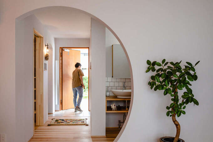 玄関からリビングへ向かう壁を半円形にして、空間を広く見せる工夫も