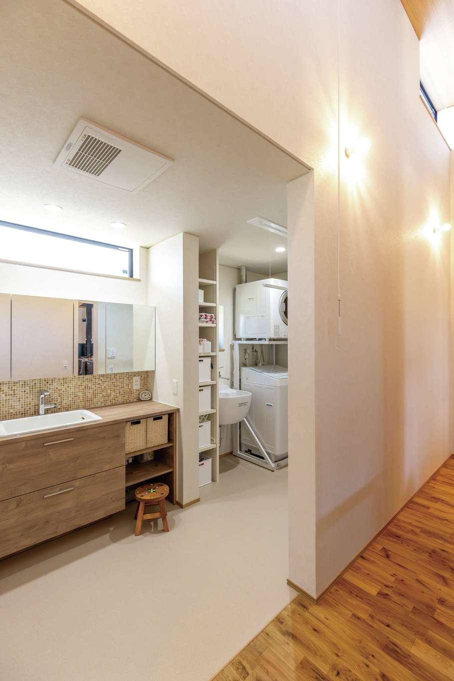 神谷綜合建設 カミヤの家【子育て、省エネ、平屋】廊下の天井高はなんと4.1m。高窓から光が降り注ぎ、北側であっても十分明るい。ランドリールームを併設し、モザイクタイルをあしらった洗面台がかわいい