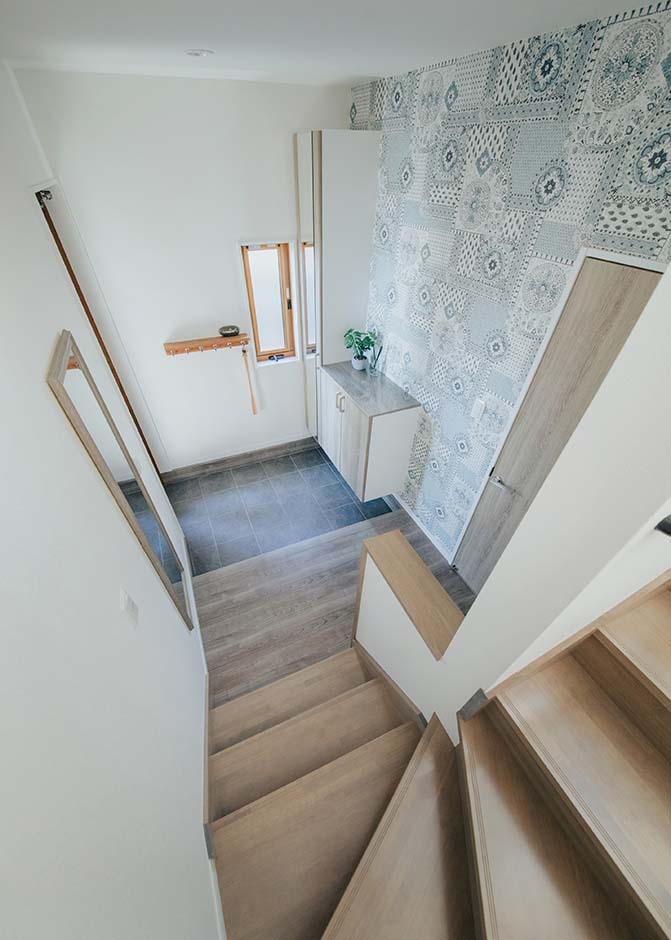 ハート住いる｜白で統一した空間に木のあたたかみをプラスした、親世帯の玄関ホール。華やかなアクセントクロスがゲストを出迎える