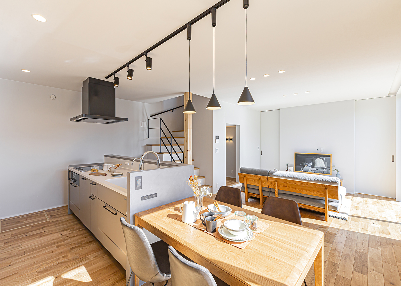 ARRCH アーチ【デザイン住宅、間取り、建築家】キッチンはアイランド型を採用し、リビング側から手元が見えないようにセニベトン仕上げの腰壁を設置。ダイニングテーブルは配膳や片付けがラクにできるようにキッチンと横並びにし、庭を眺められる位置に配置した