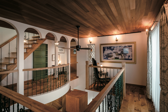 吹き抜けを囲む2階・回廊。木目の美しいブラウンと壁紙の白をベースカラーにモスグリーンの手すり柱や家具が調和し、重厚な雰囲気