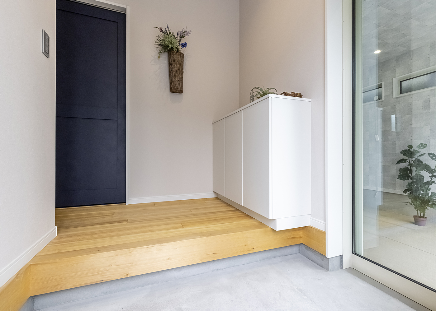 カナメクラフト（かなめ創建）【自然素材、建築家、平屋】玄関の土間部分から、ガラス窓越しに愛車を収納するガレージを見られるつくり。ホールの床には「もみの木」が使われ、優しい色合いに癒やされる