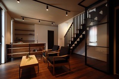 シンプルでモダンなリビング。木製の家具と温かみのある照明がくつろぎの時間を演出する。階段が調和し、空間全体が広く感じられる