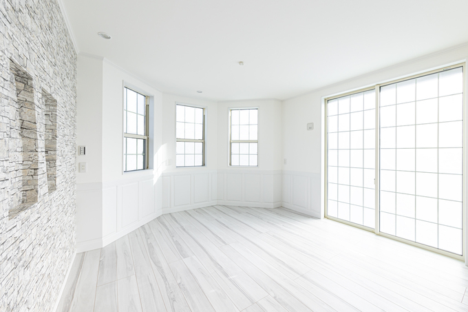 白を基調とした明るいリビング。大きな窓から自然光がたっぷり入り、開放感がある空間。シンプルで洗練された印象を与える。