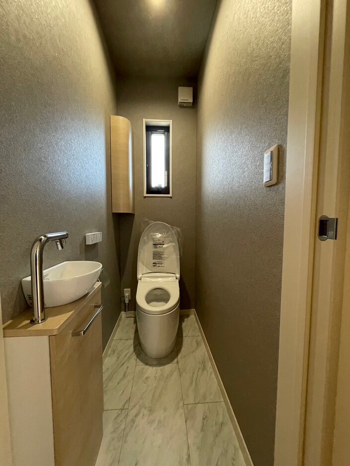 落ち着いた色調でまとめられたトイレ空間。コンパクトながらも機能的な設計で、手洗いスペースが設置されている点が特徴。