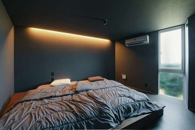 あえて斜めにベッドを配置し、空間を広く使えるように設計した主寝室。天井も壁も床もダーク調にトーンに落として、リラックス効果を高めた