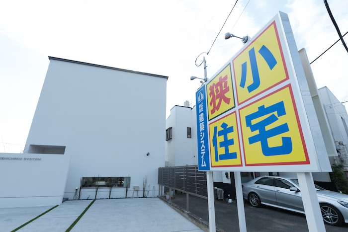 建築システム（狭小住宅専門店）【沼津市大岡2825・モデルハウス】ホワイトのキューブスタイル。玄関前に目隠しの壁を建ててデザインの統一感を出した。やわらかな灯りがこぼれるFIX窓は、足元の明かり取りと外からの目線をずらす役割が