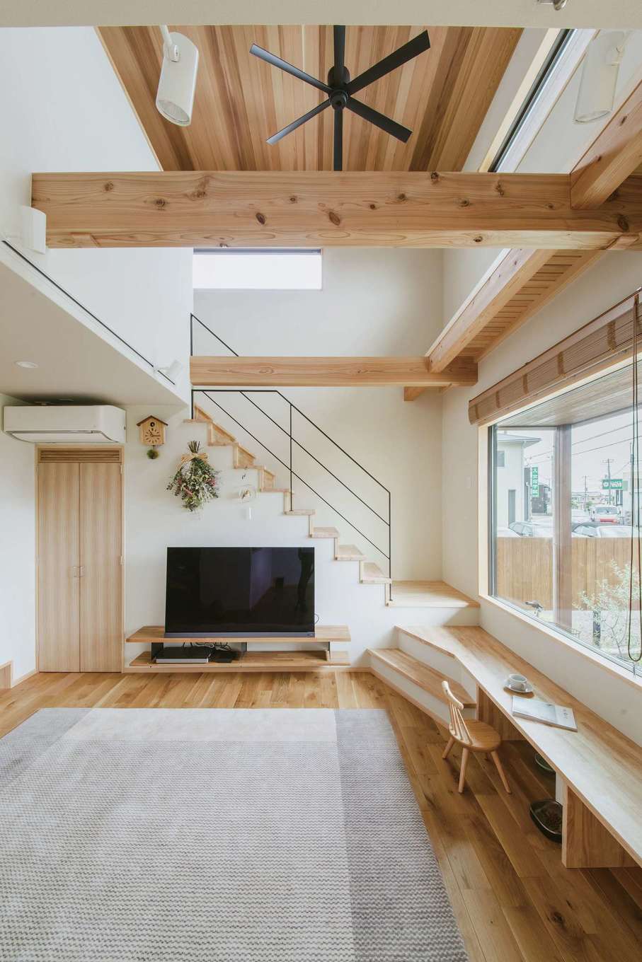 フジモクの家（富士木材）【デザイン住宅、自然素材、間取り】大らかな空間に天井に張られたスギがぬくもりをプラス。アクセントのアイアンやシーリングファンが引き締め、開放的でありながら落ち着く空間に仕上がった。デスク兼ベンチは家族にとって大切な場所に