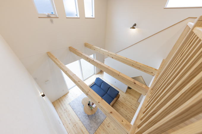 吹き抜けが印象的なリビング。開放感があり、室内に自然光がたっぷり入り込むデザインで、木の温もりが感じられる。