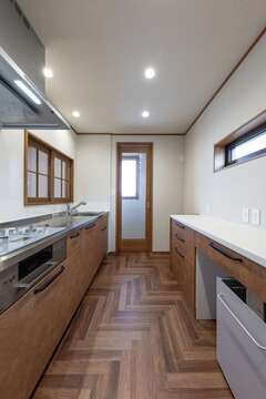 個室のような独立型キッチンには透明なガラスドアを採用。窓越しの明るい光が奥まで入り込んでくる