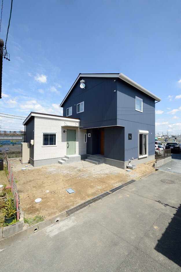 ダークブルーと白のコントラストが美しい外観デザイン。外壁はガルバリウムのようにも見えるサイディングを採用し、コストダウンを実現