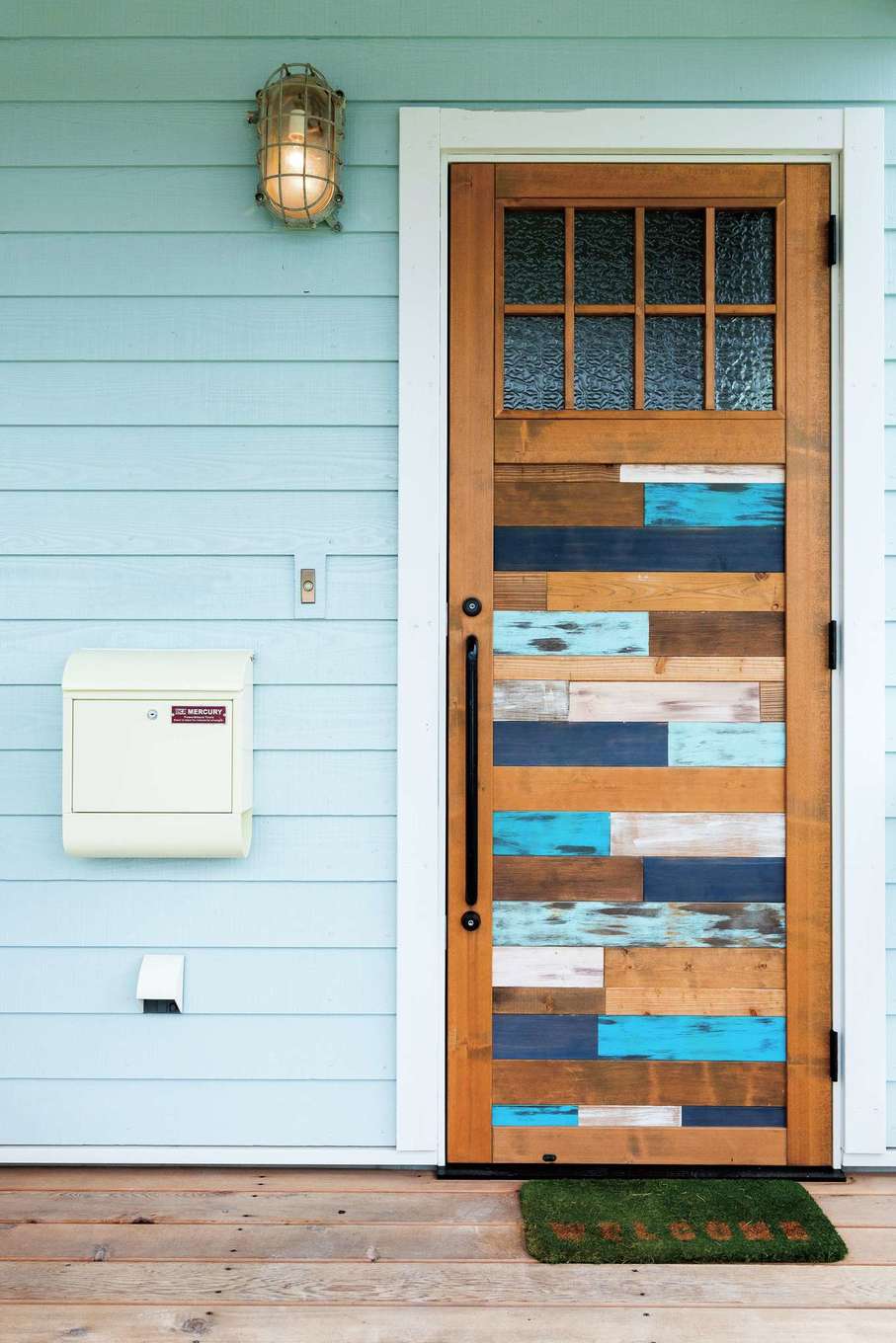 富士ホームズデザイン【デザイン住宅、建築家、インテリア】『富士ホームズデザイン』オリジナルの玄関ドア。表面はブルーを効かせて外観のアクセントに。裏面は茶色を基調にデザイン。照明はアンティークの船舶用ライト