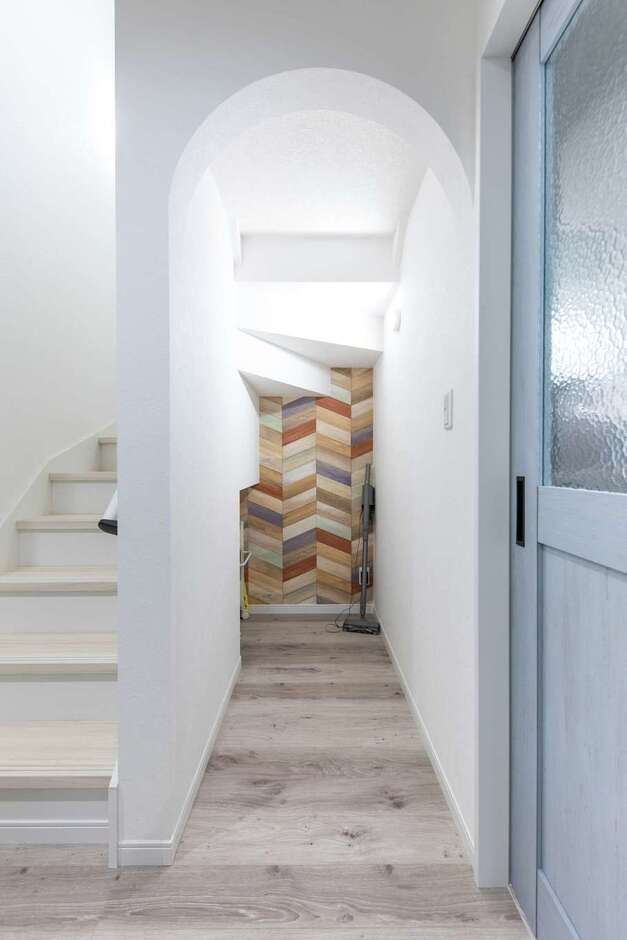 階段下は収納として有効活用。アーチの入口とヘリンボーン柄のクロスでやわらかい雰囲気に