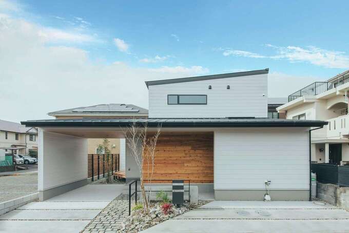 アイフルホーム焼津店 （三住建設）【焼津市柳新屋1002‐8・モデルハウス】屋根勾配を抑えた白いガルバの外観は、モダンな印象を放ち、完成前から注目を集めていた。玄関回りには無垢を張り、あたたかみをプラス。内部がうかがえないよう、通り側は開口部を減らしている