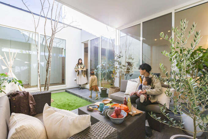 四方を建物と壁で囲った中庭テラスはプライベート感にあふれた空間。リビングと玄関ホール側の掃出窓から行き来でき、駐車場と直接つながるドアも設けてある。中庭にはシンボルツリーのガーデンと屋根付きのテラスがあり、屋外でありながら住まいの一室としてフレキシブルに活躍する