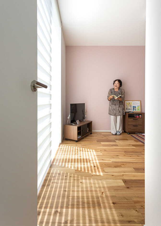 1階にはご主人のお母さまの部屋も。この部屋も芝生の庭に面し、いつもLDKと一体感が生まれている。ピンクの壁紙がアクセント。「薔薇の鉢植えを育てたり、離れた場所にある畑の世話をしたり。私も庭を楽しんでいます」とお母さま