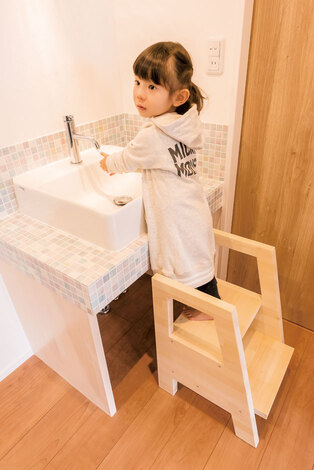 構造体やリビングの梁に使った木材の端材で作ってもらった、子ども用の小さな家具。丈夫な踏み台は、子どもが洗面台で顔や手を洗う時に便利。近い将来、母娘揃ってキッチンに立つ時にも活躍する。小さなデスクは、リビングのカウンターデスクを使うまでのお絵かき用に。天然木なので、子どもが使っても安心だ