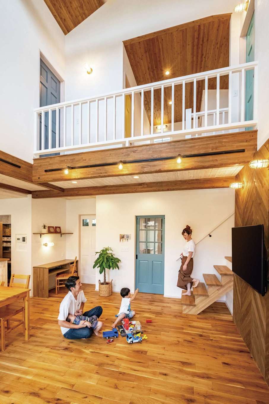 富士ホームズデザイン【デザイン住宅、間取り、スキップフロア】大きな吹き抜けとひと続きのカバードポーチによって、空間が縦横に伸び、圧倒的な開放感で満たされるLDK。床のオークと色のバランスを整えたハリや天井の無垢が、大らかさにあたたかみを添えている。2階の各部屋は、内部のクロスとドアの色を連動。空間にアクセントをつけ、楽しい気分ももたらしてくれる