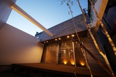 夜の中庭はムーディーな照明で彩られ、木々とウッドデッキが自然との調和を演出するスペース