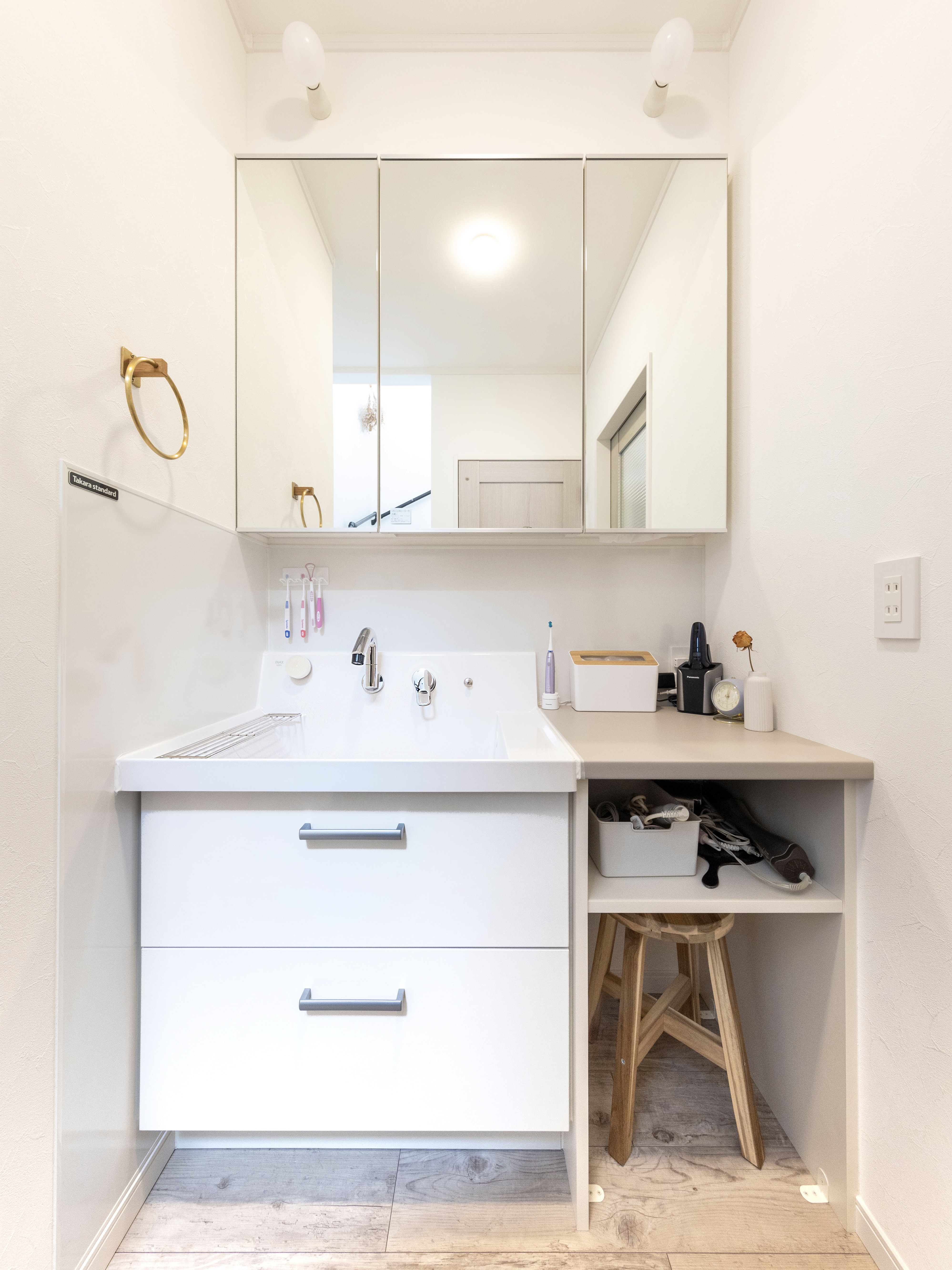 エスホーム｜廊下に設けた洗面スペースで、シンプルながら実用的なデザイン。使いやすい引き出し収納とコンパクトなカウンターが特徴。鏡付きキャビネットで収納力も充実している。