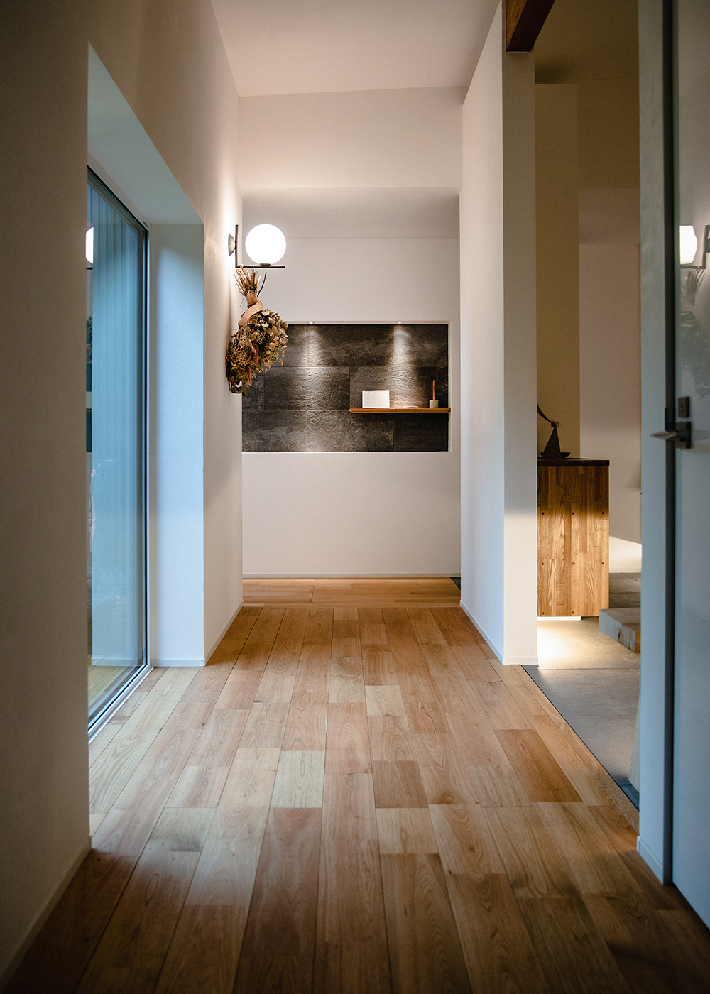ainoa.life くらはし建築【デザイン住宅、間取り、インテリア】柔らかな照明が落ち着いた雰囲気を演出し、シンプルで洗練されたデザインの廊下